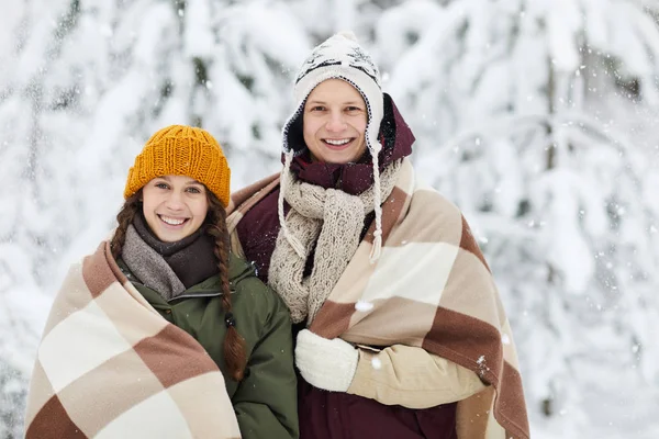 腰高的肖像爱的年轻夫妇包裹在毯子摆姿势一起在户外站在雪树对雪树在美丽的冬季森林 复制空间 — 图库照片