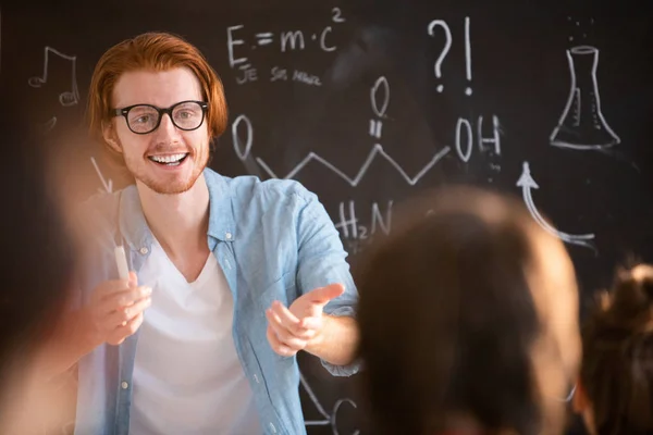 年轻开朗的老师在眼镜指着一个学生给出正确的答案 他的问题在课堂上 — 图库照片