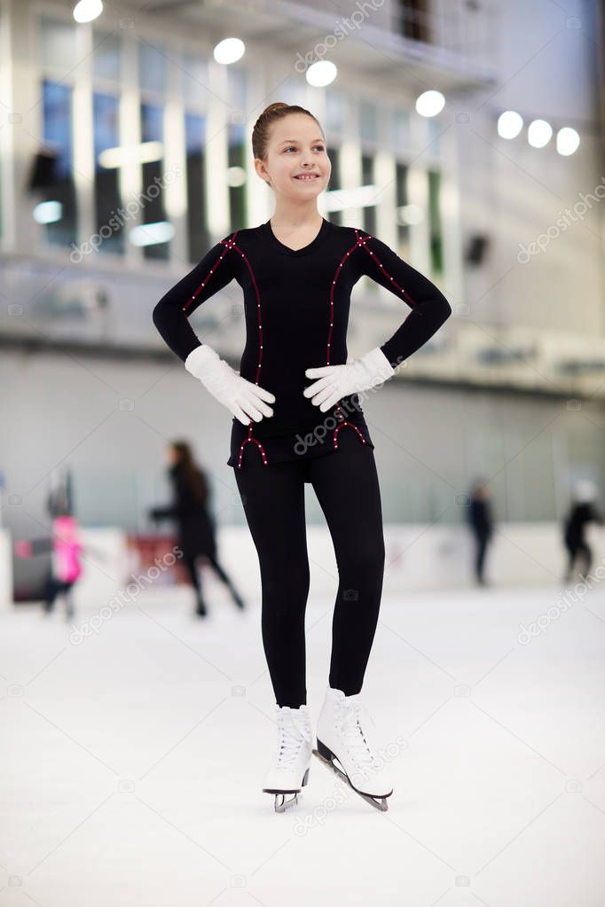 Full length portrait of teenage girl figure skating on ice rink and looking away dreamily, copy space