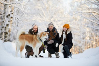 Güzel kış parkı köpek ile yürüyüş zevk mutlu ailenin tam uzunlukta portre, kopya alanı