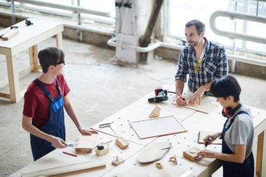 Ahşap parçaları ile masada duran ve ahşap ile çalışma ve oyuncaklar montaj sırasında sohbet modern marangozlar grup