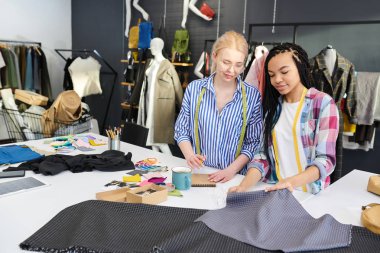 İki moda tasarımcısı kumaş iki farklı parça bakıyor ve yeni elbise dikmek için bir seçim
