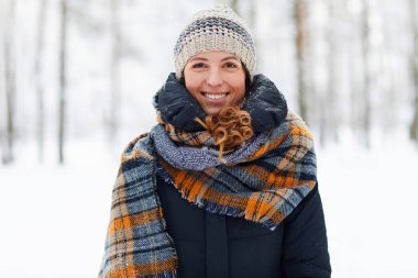 Kış ormanında kameraya bakan ve gülümseyen, kopya alan güzel genç kadının bel kadar portre