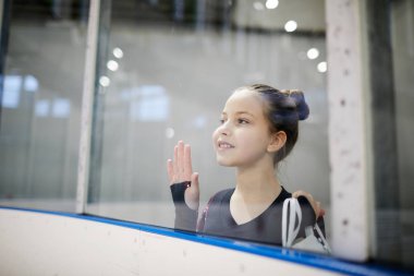 Cam dan artistik patinaj eğitimi izlerken ve hayalperest gülümseyen umutlu küçük kız Portresi, kopya alanı