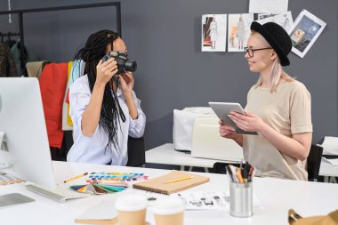 Moda tasarımcısı o dijital tablet kullanırken atölyede meslektaşı fotoğraflama