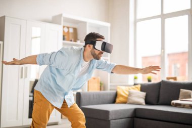 Genç adam evde gergin silah ile taşıma sırasında vr gözlüğü sanal şeylere bakarak gündelik giysiler