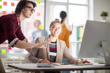 İki genç casual yöneticileri veya online bilgi tartışırken bilgisayar ekranına bakarak tasarımcıları
