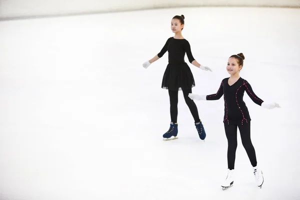 優雅にポーズアイスリンクでスケートする2人の幸せな女の子フィギュアの高角肖像画 コピースペース — ストック写真