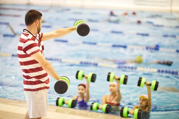 Junge Schwimmlehrerin Steht Mit Hanteln Und Trainiert Kleine Mädchen Schwimmbad — Stockfoto