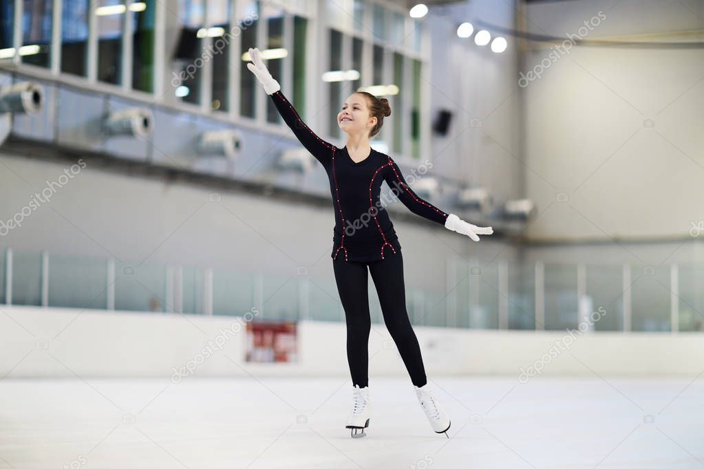 Full length portrait of graceful teenage girl figure skating on indoor ice rink, copy space