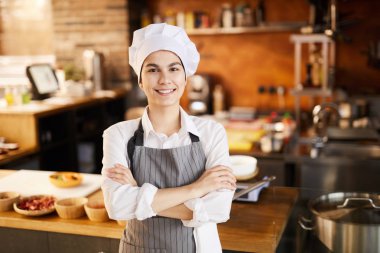 Restoran mutfağında poz verirken kameraya gülümseyen genç aşçının bel den yukarı portresi, kopya alanı