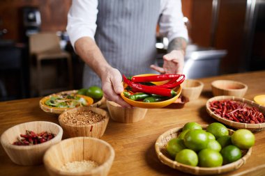 Restoran mutfağında yemek pişirirken biber ve baharat tutan profesyonel şefin orta bölüm portresi, kopya alanı