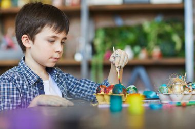 Sanat stüdyosunda Paskalya için sevimli çocuk boyama yumurta Yan görünüm portresi, kopya alanı