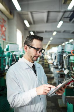 Atölye, kopya alanı modern makineler çalışırken dijital tablet kullanarak olgun fabrika çalışanı bir portre kadar bel