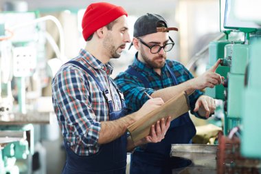 Eğitim iki yeni fabrika işçileri yan görünüm portre, atölye makine birimlerinin çalışmasını açıklayan, kopya alanı