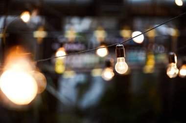 Karanlıkta bükülmüş kablolara asılı parlak ışıklı ampullerin yakın çekim, tasarım konsepti