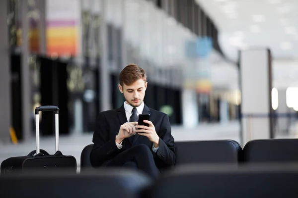 年轻商人的肖像使用智能手机坐在皮椅在机场 复制空间 — 图库照片