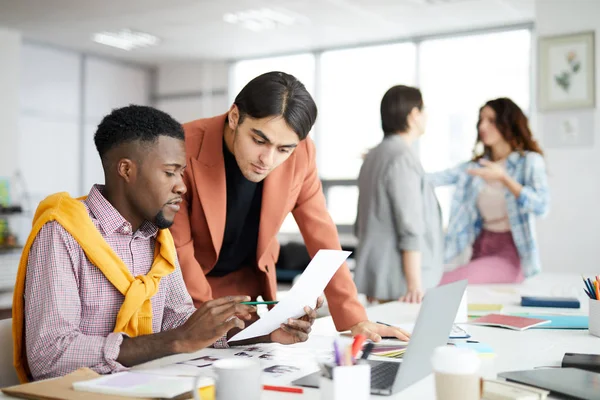 Portrait of diverse business team working in modern office with focus on African-American man holding document, copy space