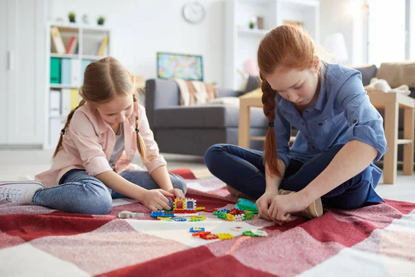 全长肖像的少女玩与小妹妹坐在地板上在家里 复制空间 — 图库照片