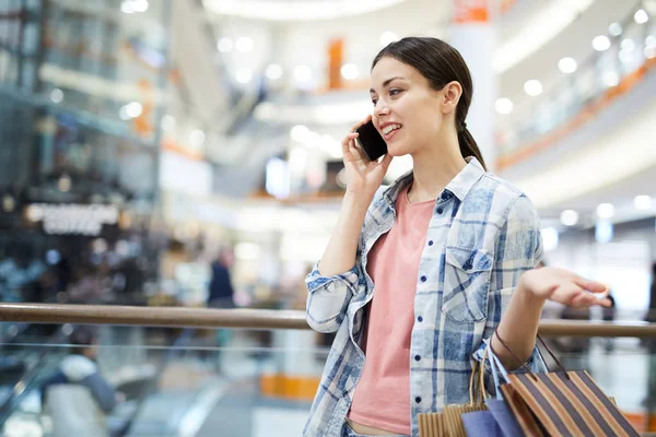 微笑积极年轻女子在休闲衬衫站在现代购物中心 并交谈手机 同时与朋友讨论购买 — 图库照片
