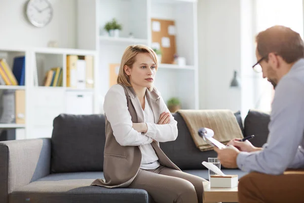 Young Confused Woman Her Arms Crossed Chest Sitting Couch Listening — 스톡 사진