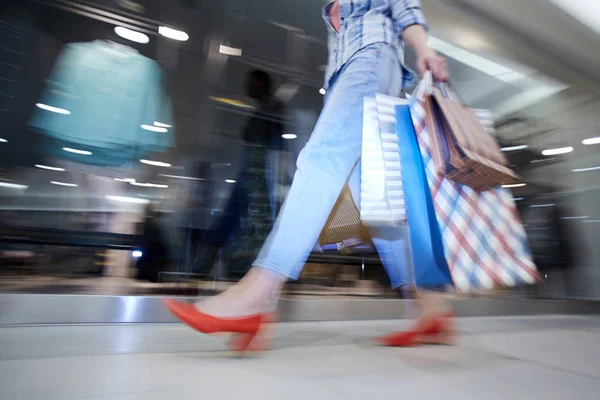 商场走廊里拿着纸袋的女士购物狂的模糊动作 不知名的女人在商店橱窗边走 — 图库照片