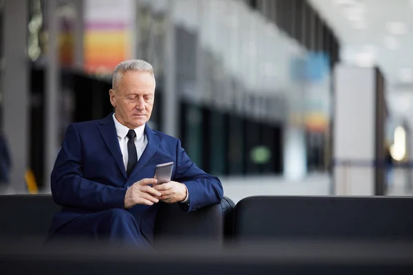 Porträtt Framgångsrik Senior Affärsman Med Smartphone Sitter Läderfåtölj Lobby Eller — Stockfoto