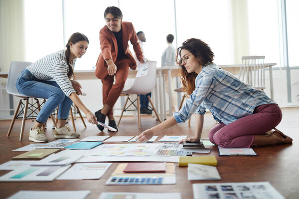 Full length  portrait of creative business team planning project drawing roadmap on floor in office, focus on foreground, copy space