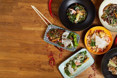 Ahşap masa üzerinde birkaç Asya yemek yemekleri üst görünüm kompozisyon, kopya alanı