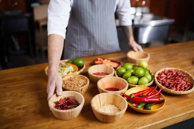 Restoran mutfağında yemek pişirirken aromatik baharatlar seçen profesyonel şefin orta bölüm portresi, kopya alanı