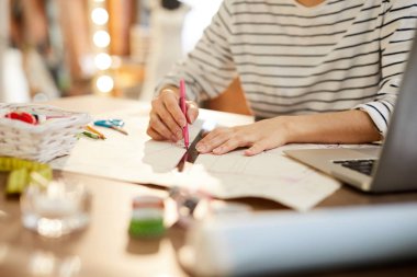 Cetvel ve fosforlu kalemle genç tasarımcı mevsimlik koleksiyon üzerinde çalışırken yeni bir taslak yapıyor.