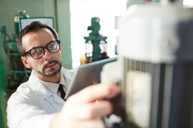 Atölye, kopya alanı makine üniteleri kurarken dijital tablet kullanarak olgun fabrika işçisi portresi
