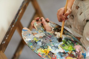 Sanat sınıfında şelat üzerinde resim yaparken tanınmayan kız tutma sanatçılar palet ve karıştırma renkleri Closeup, kopya alanı