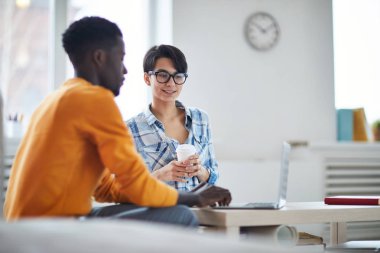 Young African-american businessman making presentation to his colleague or discussing some working points at break