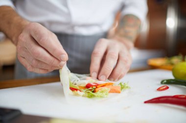 Restoran mutfağında yemek pişirirken sebze ruloları yapan profesyonel şefin yakın çekim, kopya alanı