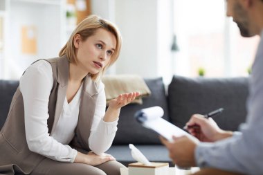 Üzgün genç kadın zor durum hakkındaki duygularını açıklama sırasında psikolog bakıyor