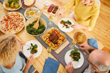 Rahat giyim masada oturan ve taze salata yeme ciddi olgun arkadaşlar doğrudan yukarıdaki görünümü, onlar lezzetli akşam yemeği zevk