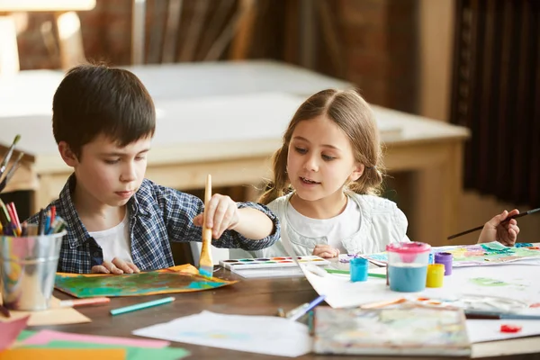 家のテーブルに座って一緒に絵を描く2人の子供の男の子と女の子の肖像画 — ストック写真