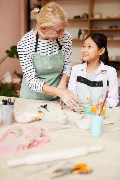 アジアの女の子が陶芸教室で手作りの陶磁器を作るのを手伝う笑顔の成熟した女性の肖像画 コピースペース — ストック写真