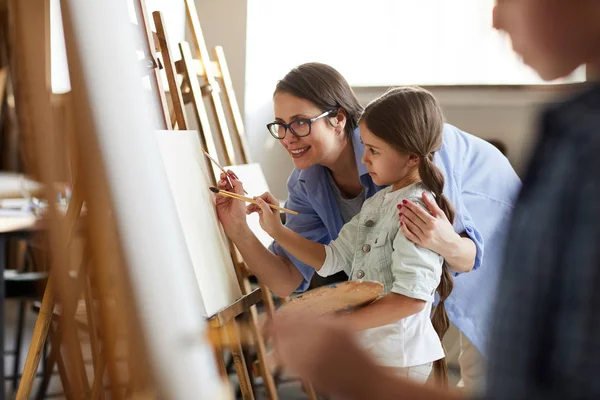 Портрет Усміхненої Жінки Вчительки Яка Допомагає Маленькій Дівчинці Малювати Мольберті — стокове фото