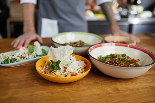 Close up of several Asian food dishes on wooden table in restaurant, copy space