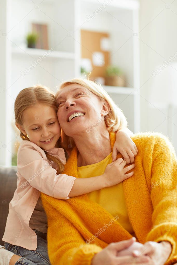 Portrait of cute little girl embracing mature woman and laughing playfully