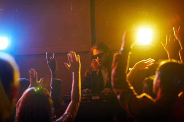 Gece kulübünde kalabalığın önünde performans yaparken kayıt pikapkullanarak güneş gözlüğü Ciddi konsantre serin Dj