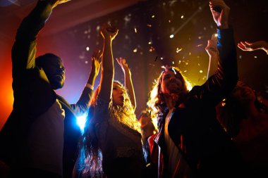 Gece kulübünde müzik konserinde konfeti düşen ve havada el sallayarak altında dans kaygısız heyecanlı insanların grubu