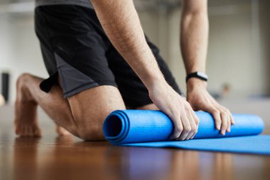 Spor salonunda yoga eğitimi nden sonra dizlerinin üzerinde duran ve egzersiz minderi dışarı haddeleme tanınmayan adam yakın çekim 