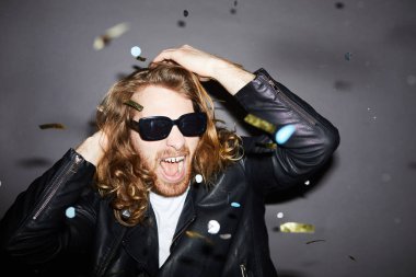 Duygusal çılgın hipster sakallı genç adam güneş gözlüğü ve siyah ceket çığlık giyen ve partide eğlenirken elele başını tutarak