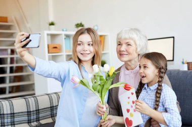 Evde büyükannelerin doğum gününü kutlarken selfie çeken üç nesil kadının portresi, kopya alanı