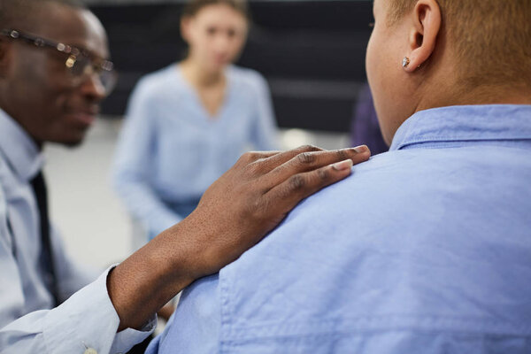 Closeup of unrecognizable African man comforting woman during group therapy session with psychologist, copy space