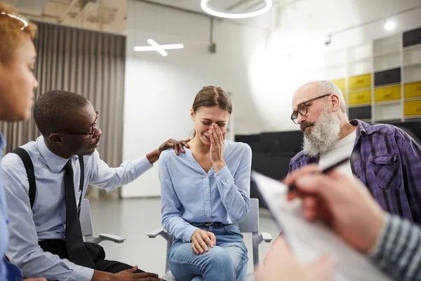 Portrait of young woman crying hysterically during therapy session in support group, copy space