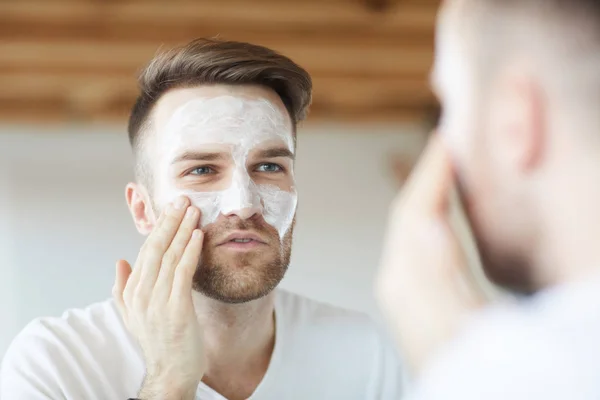 Retrato Cabeza Hombros Joven Guapo Aplicando Mascarilla Mirando Reflejo Espejo — Foto de Stock